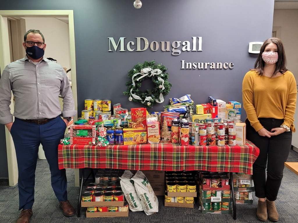 Two people stand by table with over 1000lbs of food to the local foodbank from McDougall Insurance in Arnprior