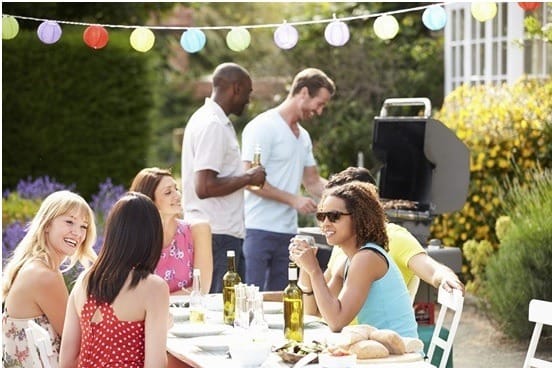 people gathering outside for a BBQ, sitting on patio chairs