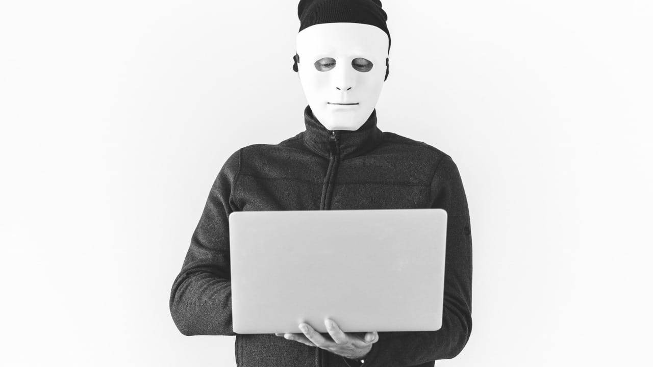 masked person holding laptop