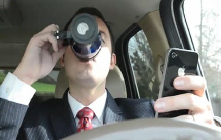 Person drinking coffee and looking at phone while driving