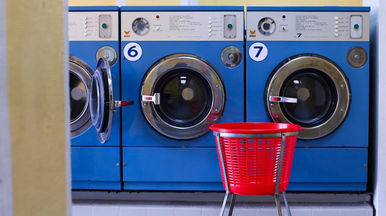 Three blue clothes dryers with a red basket in front