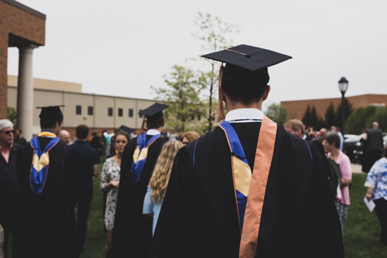 The back of a person walking wearing graduation gown and hat