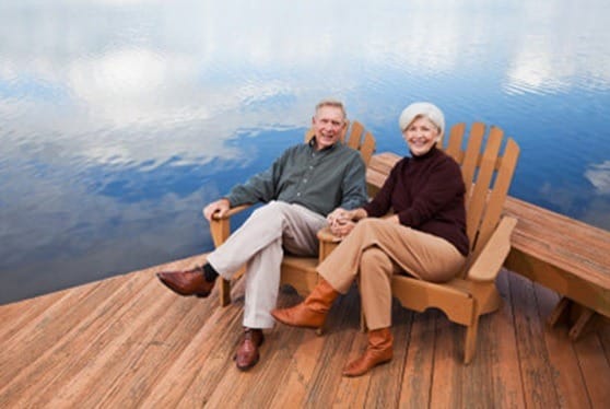 A couple on a deck smiling with the water in the background