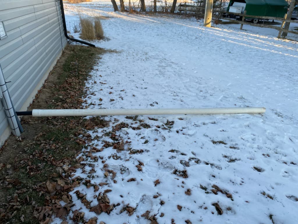 sump pump with white pipe extending away from foundation