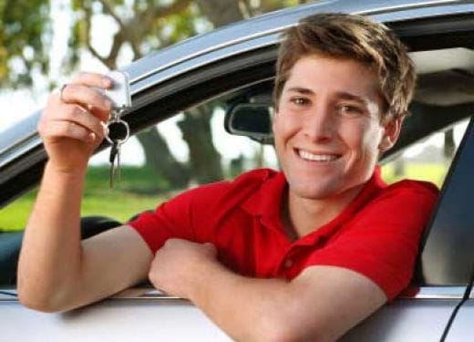 Young driver holds car keys in hand, looks out the window with a smile