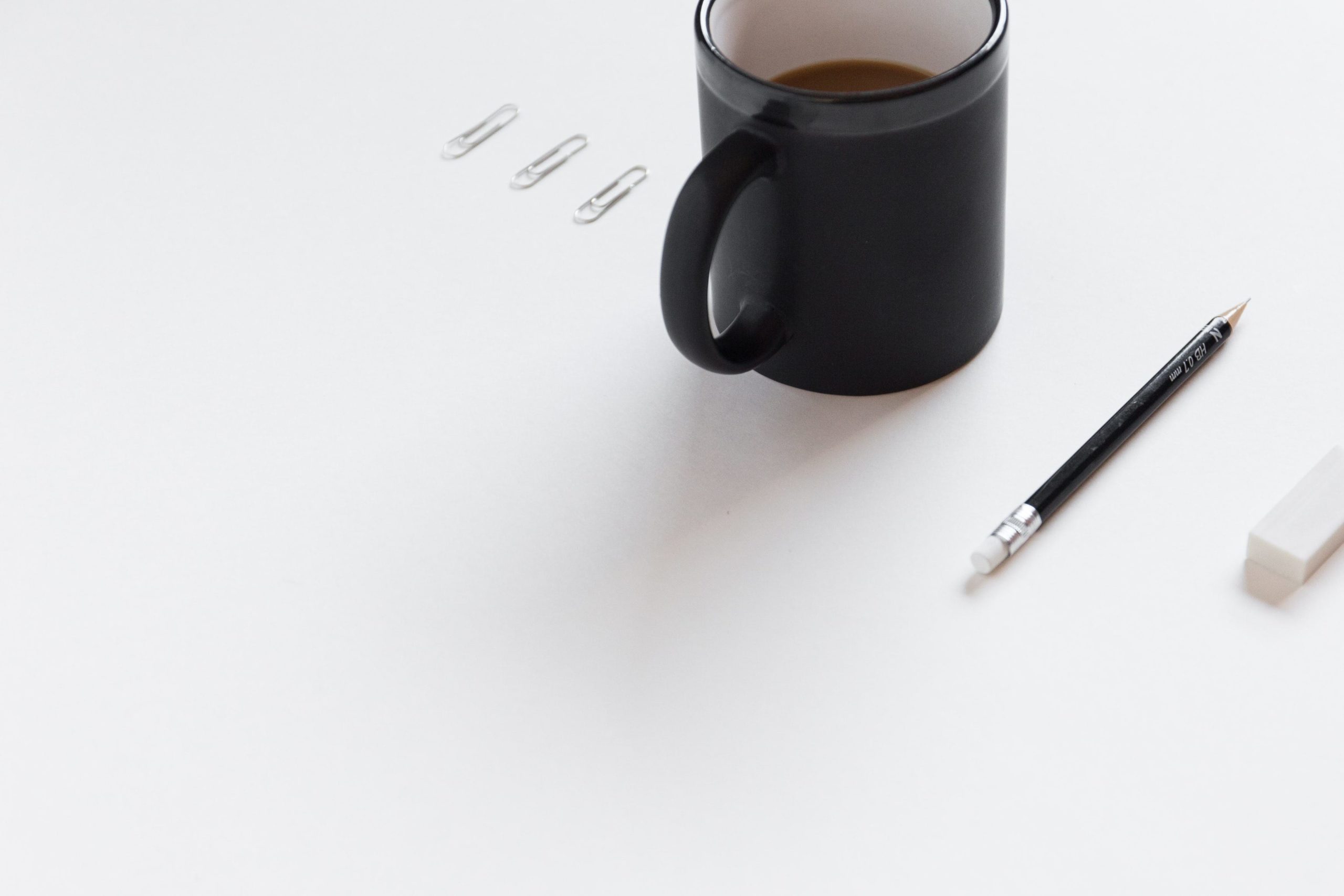 white paper with pencil, coffee cup on table