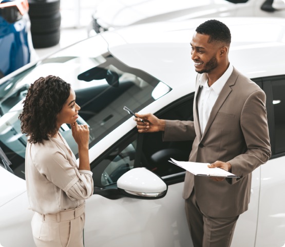 Car Sales Manager Showing car To Buyer Standing In Luxury Automobile Dealership Store. Buying Vehicle Concept