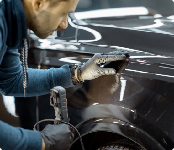 Car service worker examining vehicle body for scratches and damages, taking a car for professional auto detailing. Professional body car inspection concept