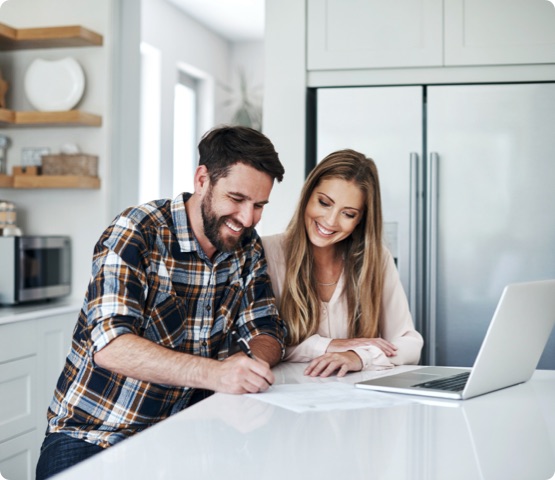 couple using a laptop to go through financial paperwork at home