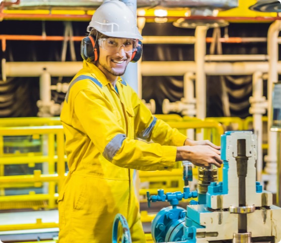 Young man in a yellow work uniform, glasses and helmet in industrial environment,oil Platform or liquefied gas plant.
