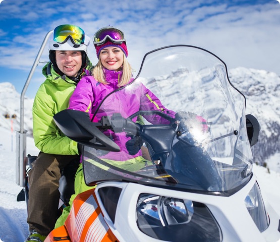 Two people riding a snowmobile on their vacation in the Alps