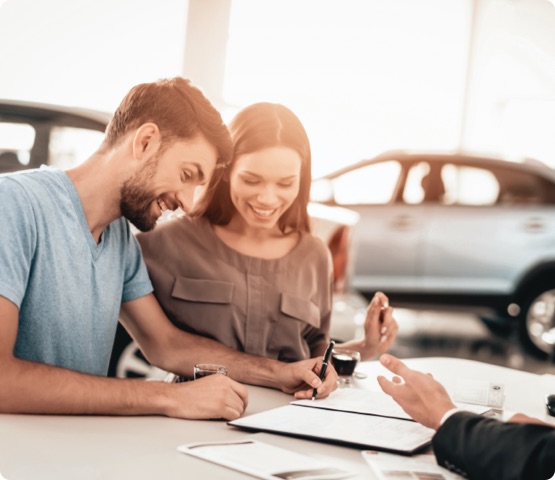 Happy Young Family Are Signing A Contract To Buy A Car. Dialogue With Dealer. Cheerful Customer. Automobile Salon. Make A Decision. Cup Of Coffee. End Of A Deal. Good Offer. Buyer And Seller.