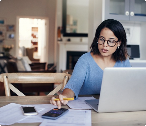 Shot of a person using a laptop and calculator while working from home