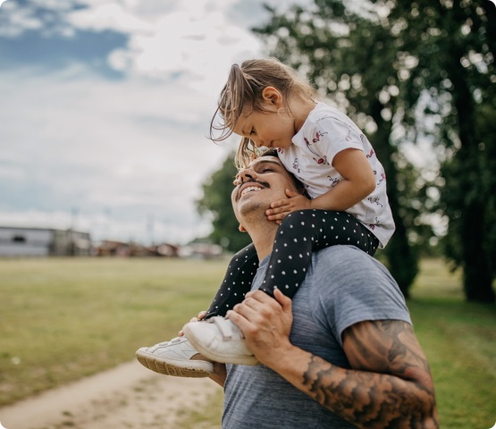 Father holds daughter on shoulders.