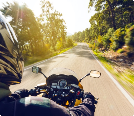 Motorcycle rider speeding down on an empty country road from over rider