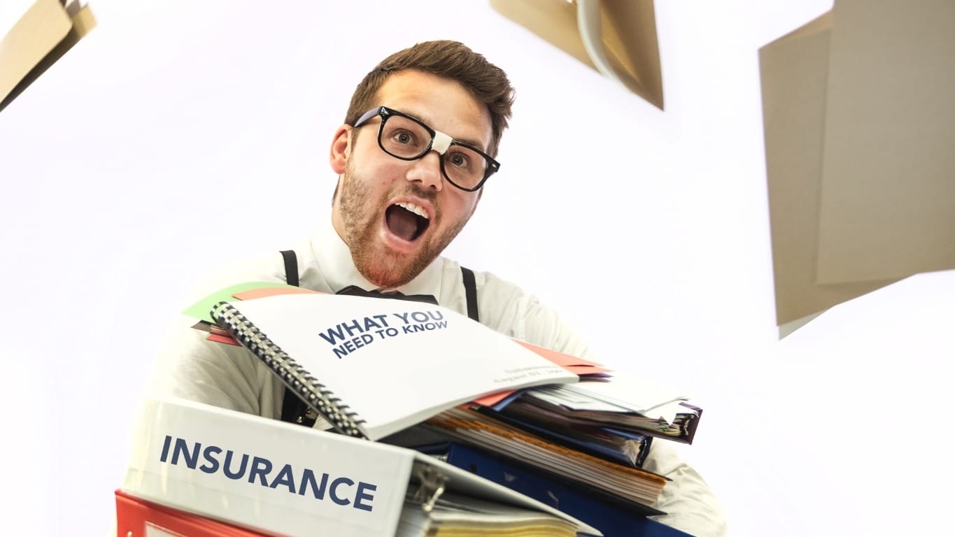 Person sitting with insurance booklets on lap, other books flying up in air