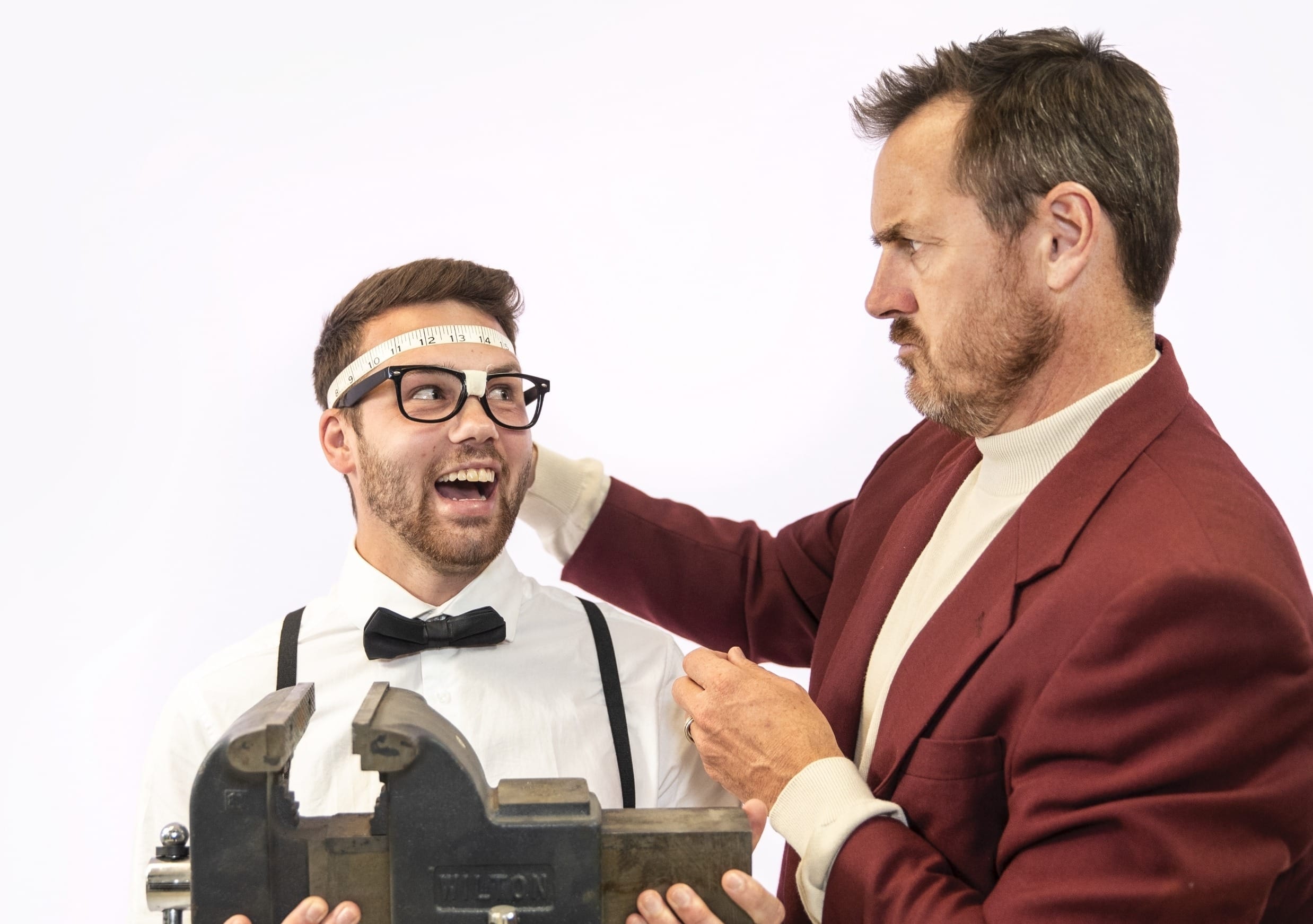 2 people playing around with measuring tape and weight scale, making silly faces