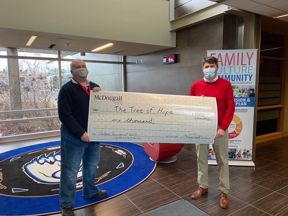 Two people hold large cheque worth $1000 to The Tree of Hope