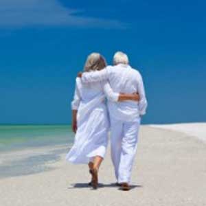 Retired couple on white sandy beach with sunny skies