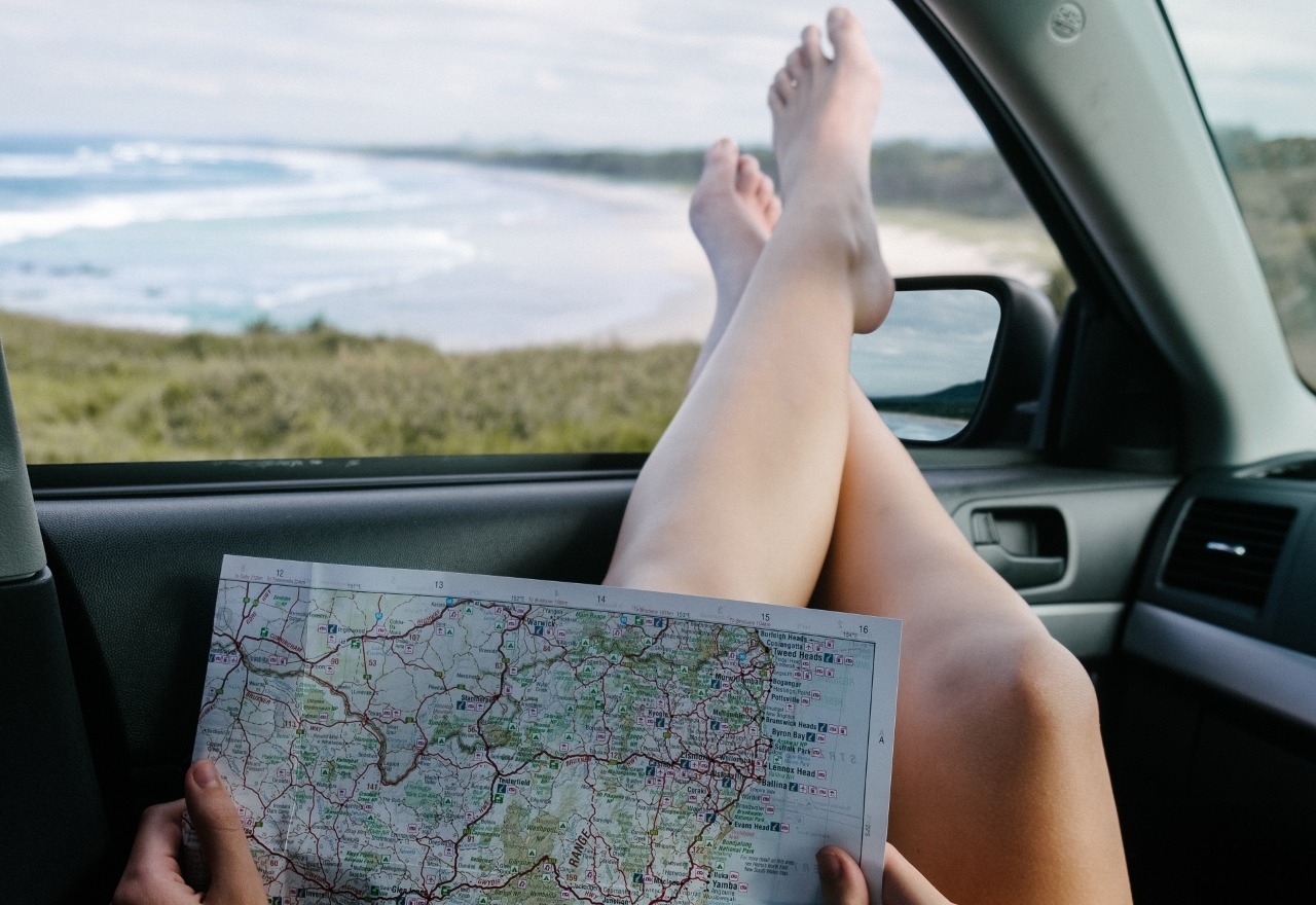 person's feet up on dashboard holding map planning road trip