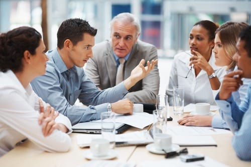 An insurance broker talking to a team of 5 people in an office building