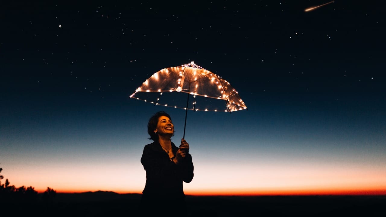 lady holding lit-up umbrella at dusk