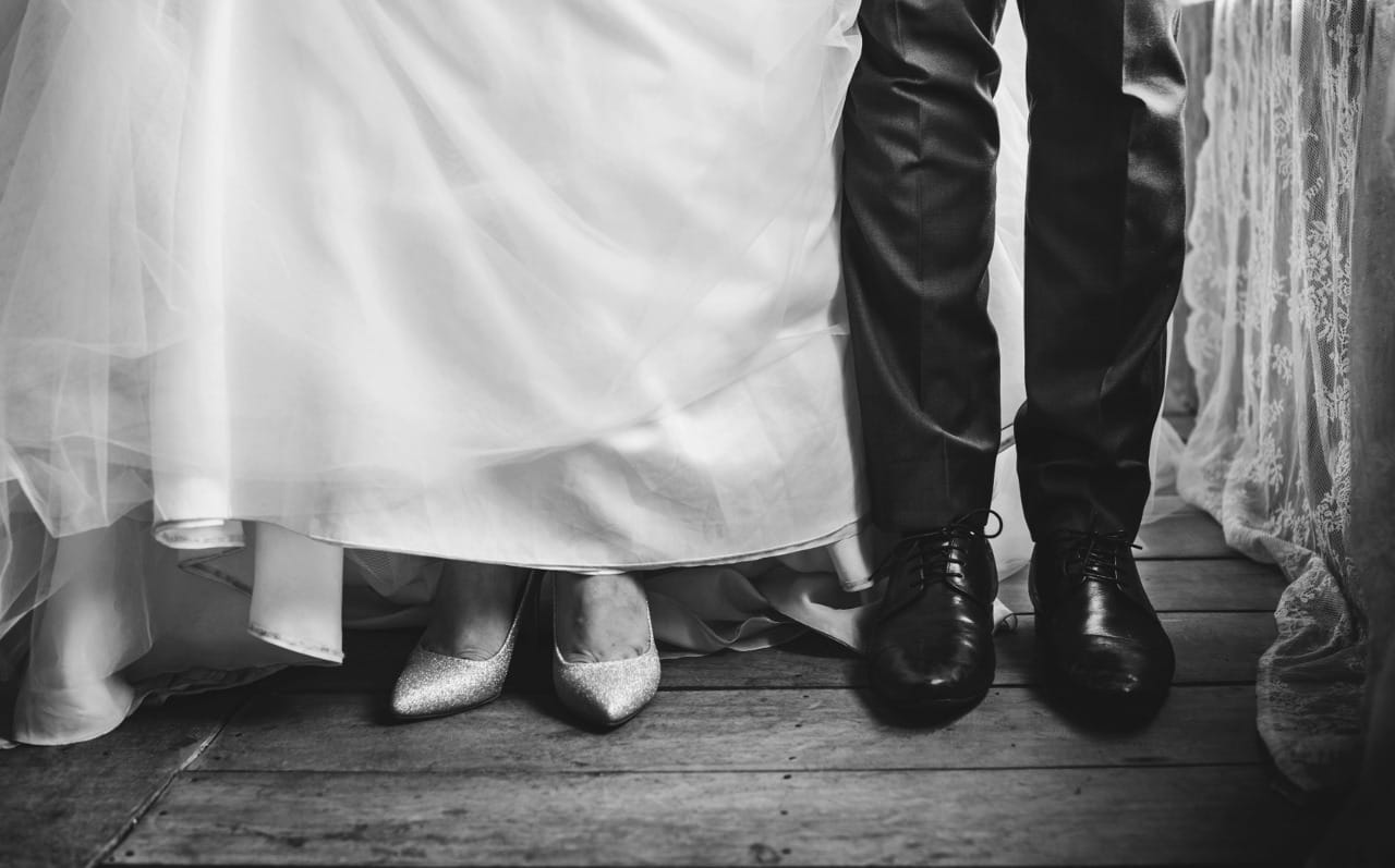 couple standing in their wedding attire, only feet and legs showing