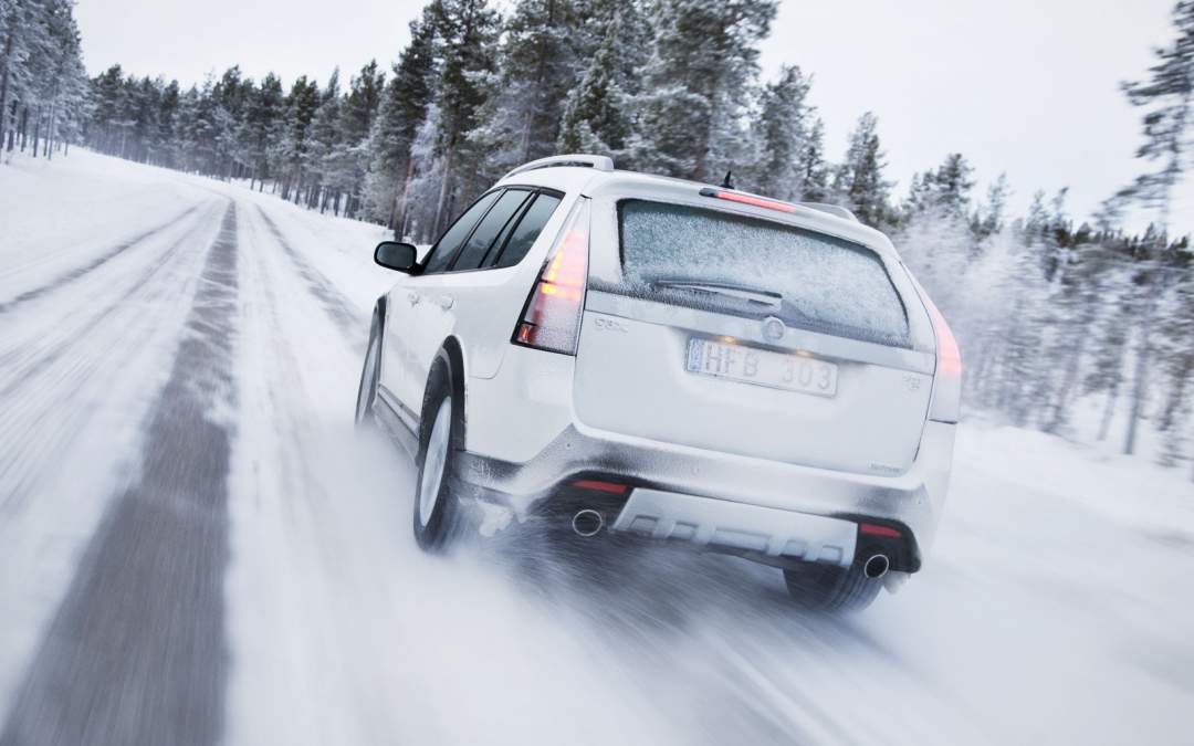 A white SUV drives in winter road conditions