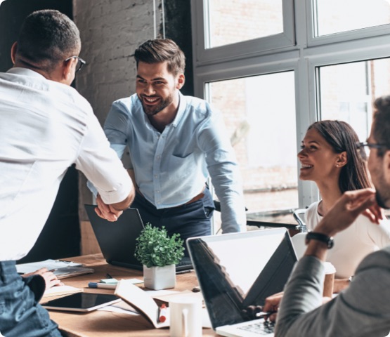 Young modern men in smart casual wear shaking hands and smiling while working in the creative office