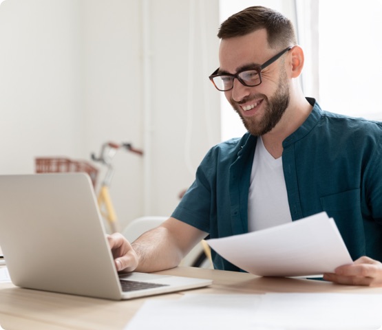 Happy young businessman in eyeglasses working on computer