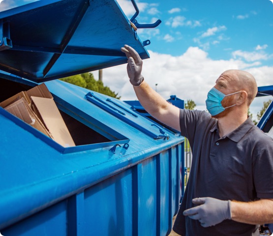 A redhead middle aged man recycling paper at a neighbourhood environmental recycling centre in the daytime during the corona virus outbreak