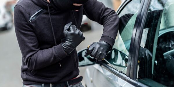 burglar attempting car theft by opening window of a vehicle with screw driver