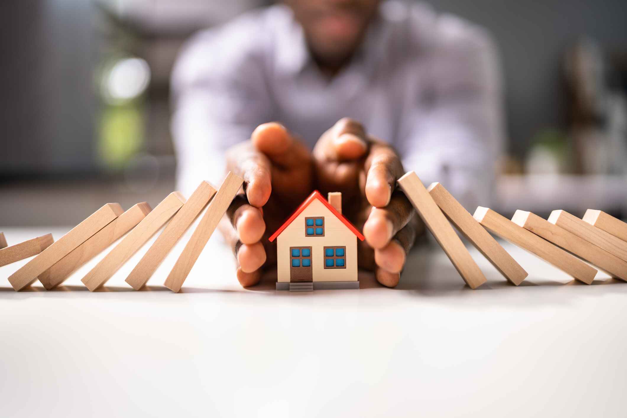 man protecting a small toy home